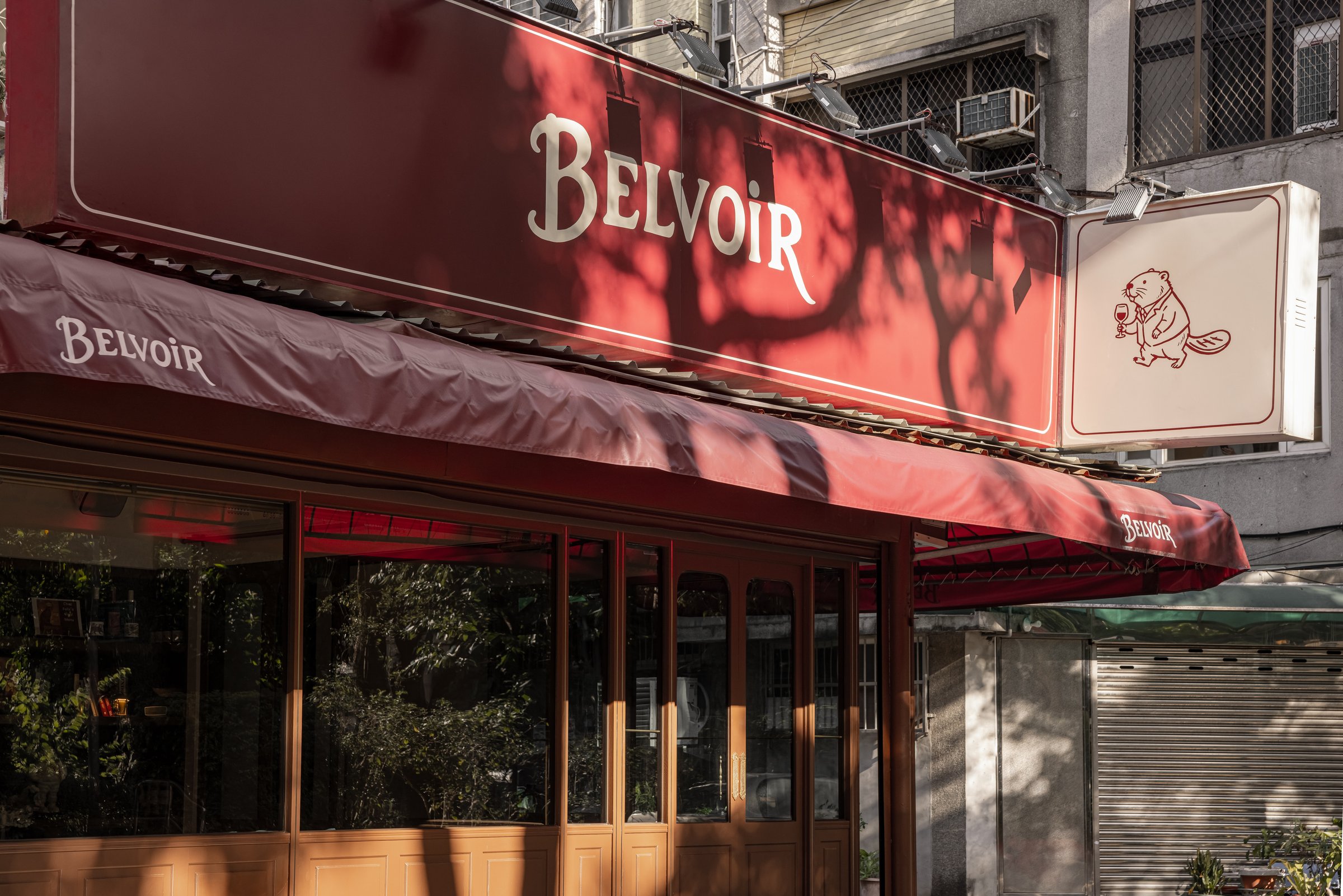 Belvoir 河狸｜餐飲空間設計 — 招牌與遮陽棚，樹影打在酒紅底上