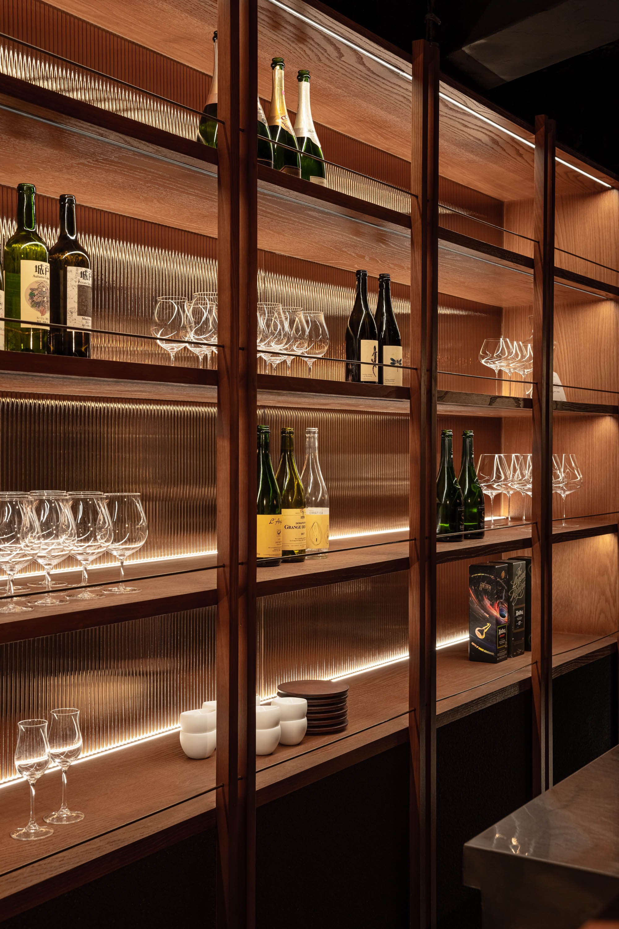VDF Wine Bar|餐飲空間設計 — 酒櫃牆架,酒瓶與酒杯在燈光下排開