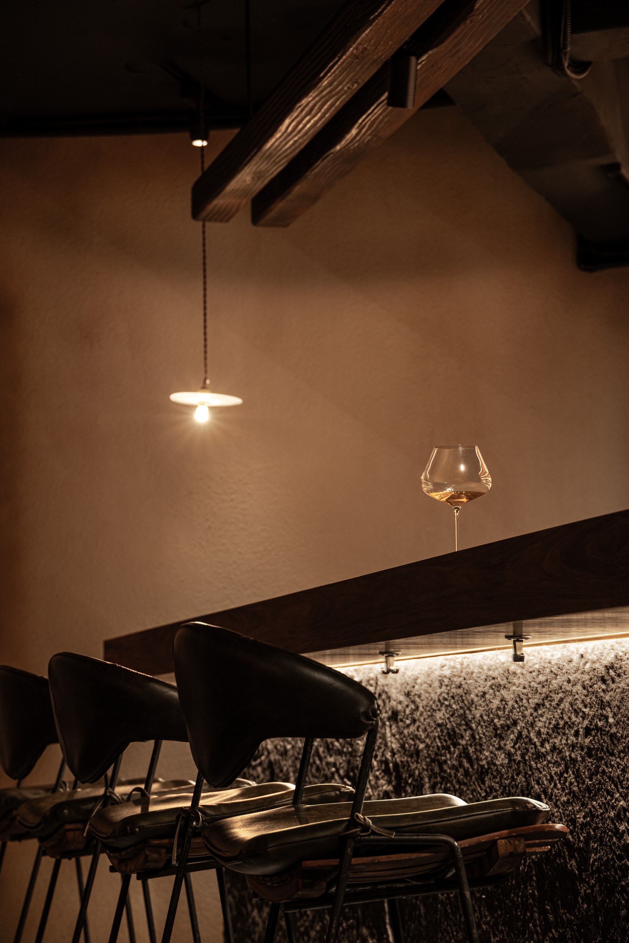 VDF Wine Bar|餐飲空間設計 — 吊燈、木梁與吧椅,石材檯身上緣的暖光